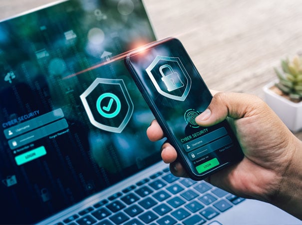 Smarttelefon med multifaktorautentisering vist foran bærbar PC. Beskytter persondata når datainnbrudd blir personlig for norske virksomheter. Som del av en sterk sikkerhetskultur med fokus på digital beskyttelse.