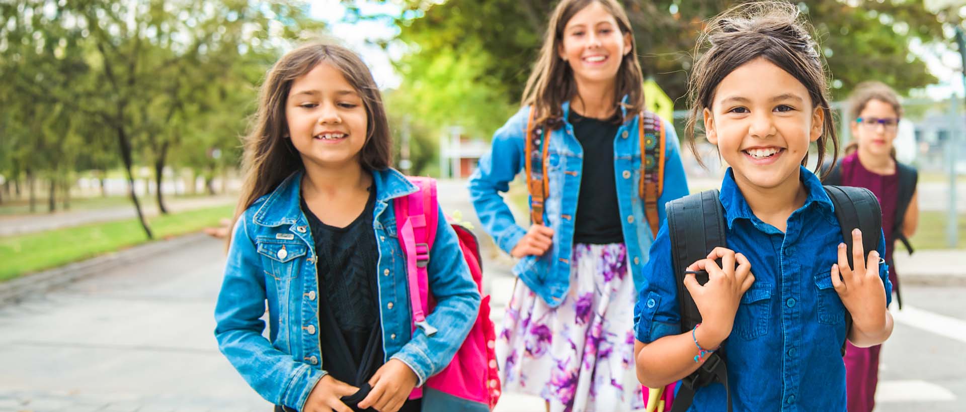 Smilende barn i grunnskolealder i klasserommet, hvor en gutt med briller holder en smarttelefon. Bildet symboliserer Visma Flyt Skole, med fokus på moderne skoleadministrasjon for grunnskolen.