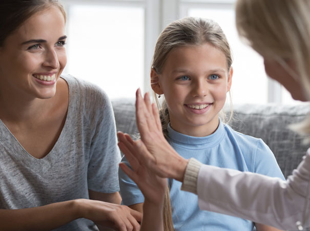 Smilende barn og mor i samtale med en saksbehandler. KI i kommunal sektor frigjør tid til de viktige møtene mellom mennesker.